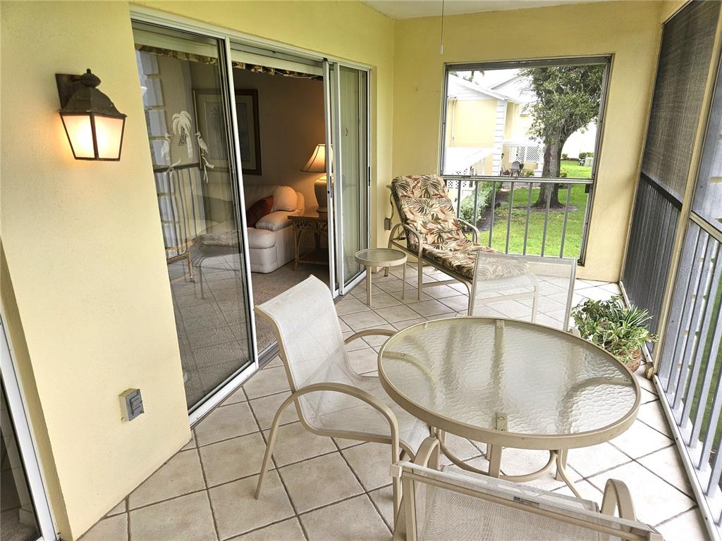 A screened-in patio features tile flooring, a glass-topped table, chairs, and a lounge chair — 418 CERROMAR COURT UNIT 257, VENICE, FL