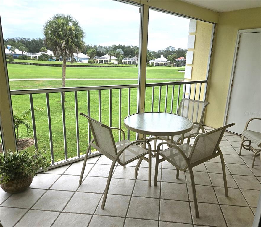 A screened-in balcony features tile flooring, patio furniture, and a view of a golf course — 418 CERROMAR COURT UNIT 257, VENICE, FL