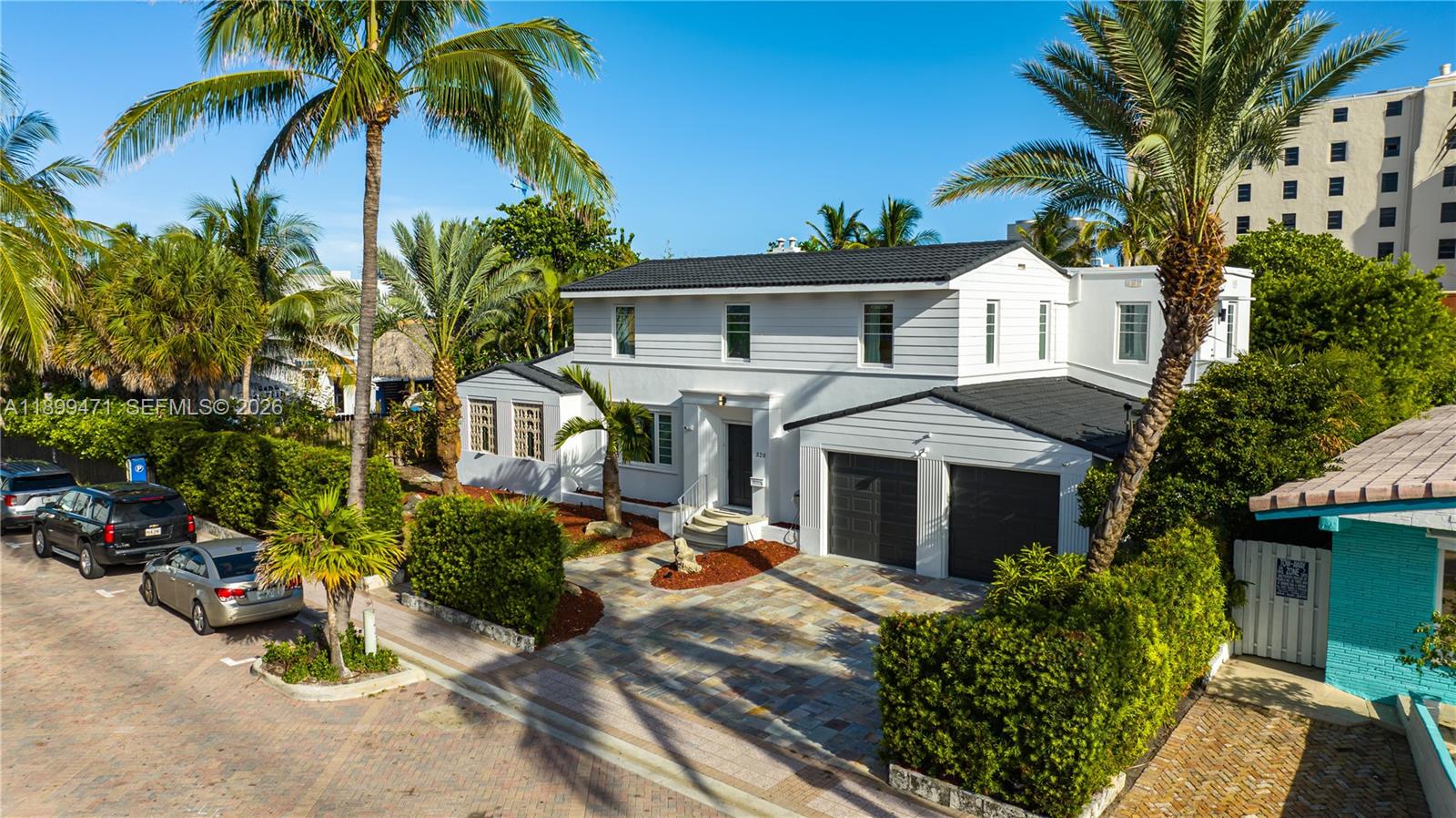 A two-story white house with a dark roof and a stone driveway sits among palm trees — 320 Polk St, Hollywood FL 33019, HOLLYWOOD, FL