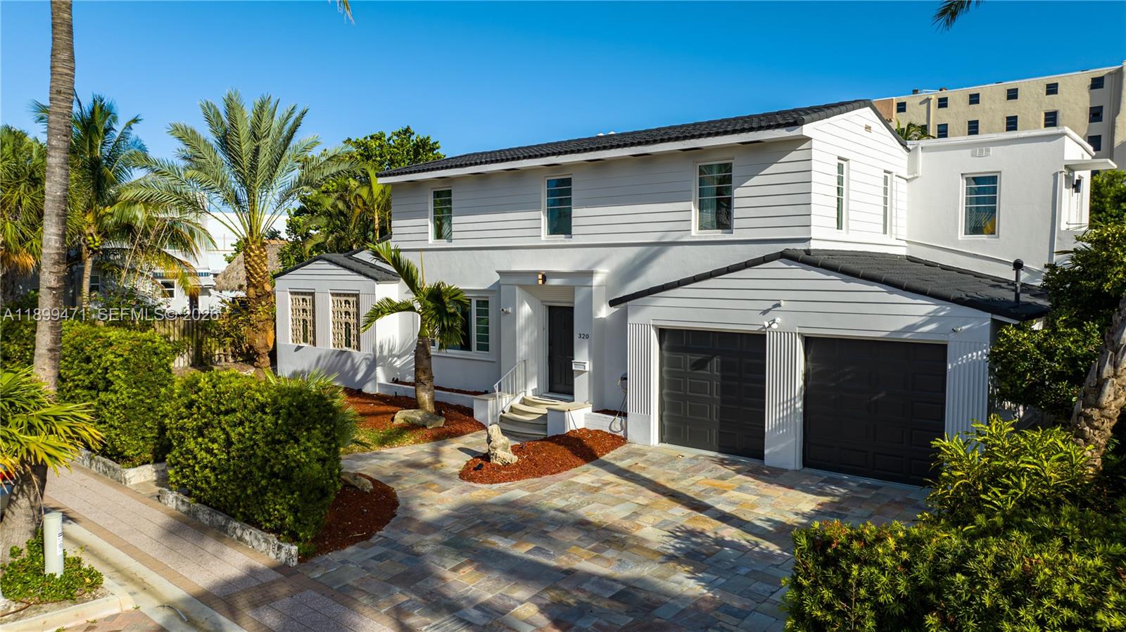 A two-story white house with a dark roof, two-car garage, and stone driveway — 320 Polk St, Hollywood FL 33019, HOLLYWOOD, FL