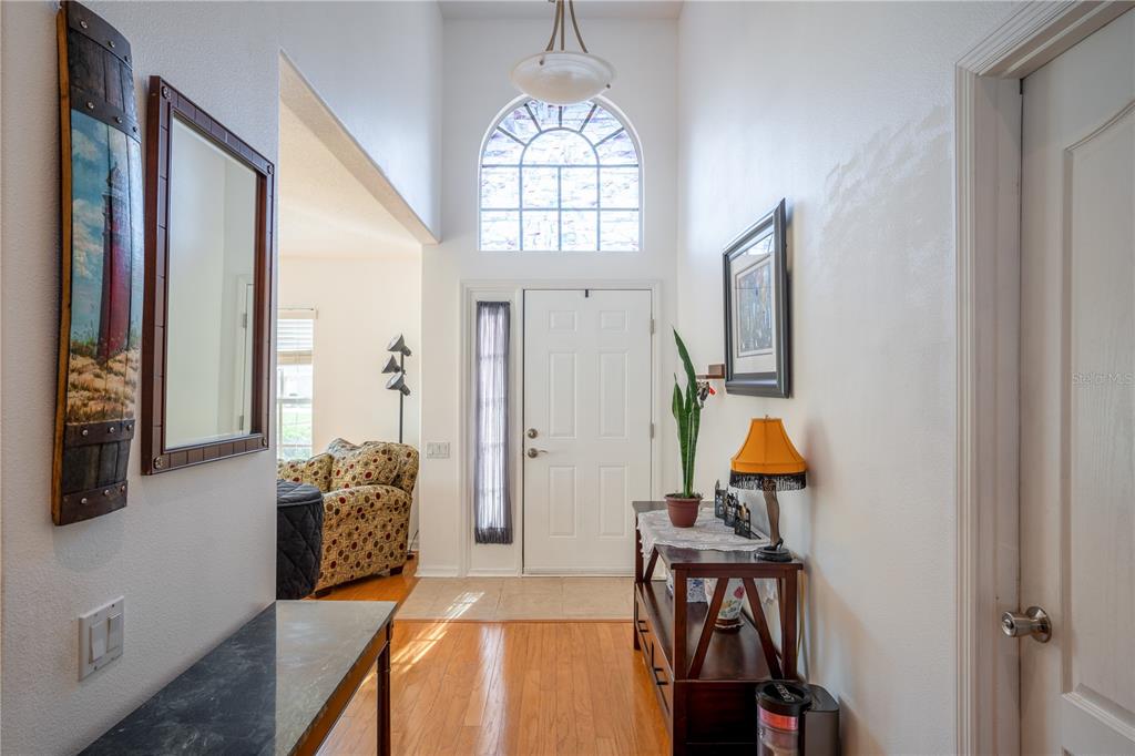 A bright entryway features hardwood floors, a high ceiling with an arched window, and furniture — 624 N LAKE BOULEVARD, TARPON SPRINGS, FL