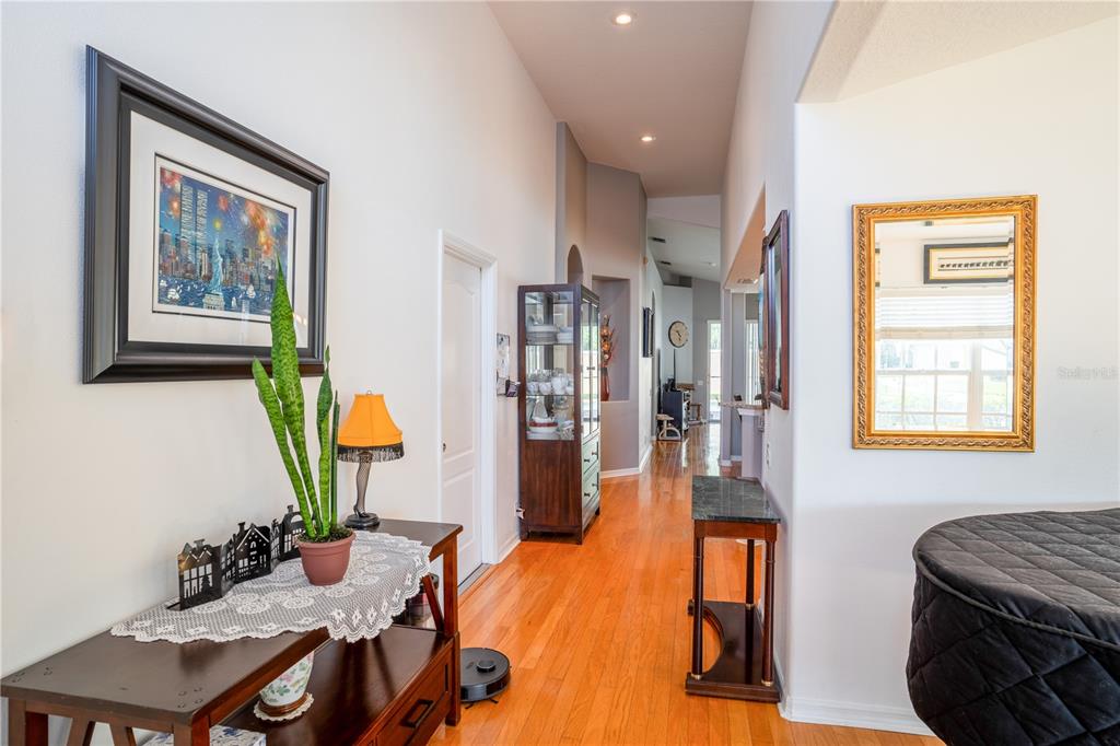 A hallway with hardwood floors leads toward an open living area with a display cabinet — 624 N LAKE BOULEVARD, TARPON SPRINGS, FL