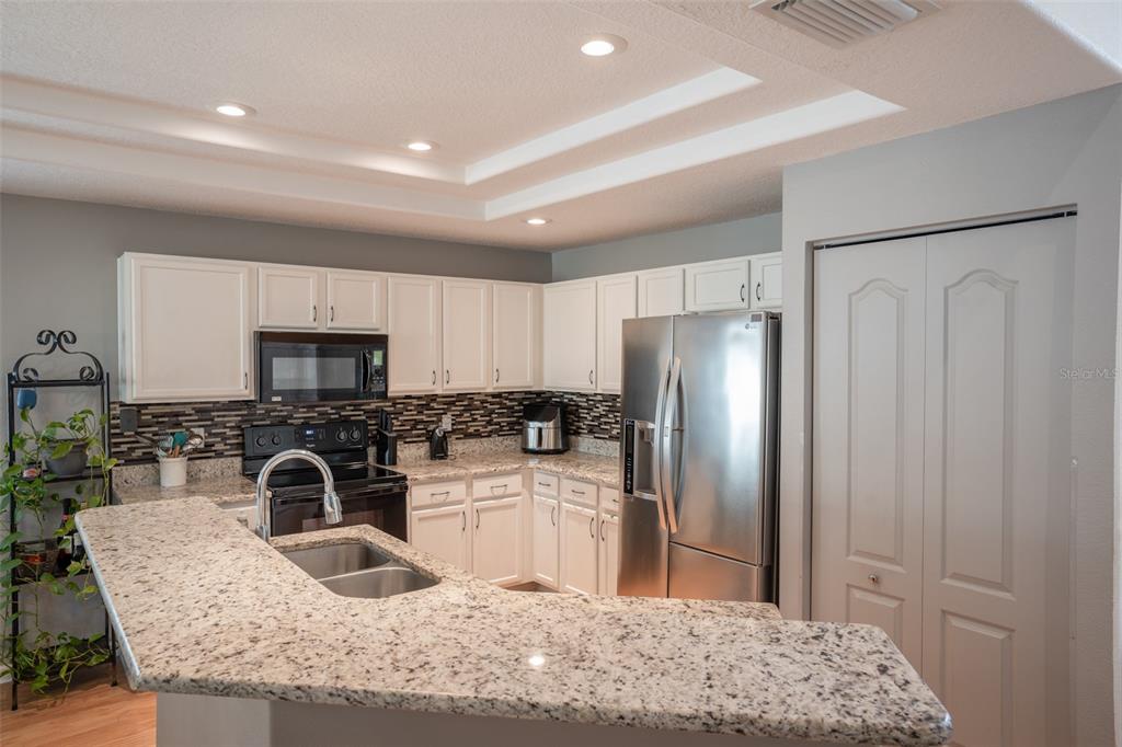 A kitchen features white cabinets, granite countertops, stainless steel appliances, and a breakfast bar — 624 N LAKE BOULEVARD, TARPON SPRINGS, FL