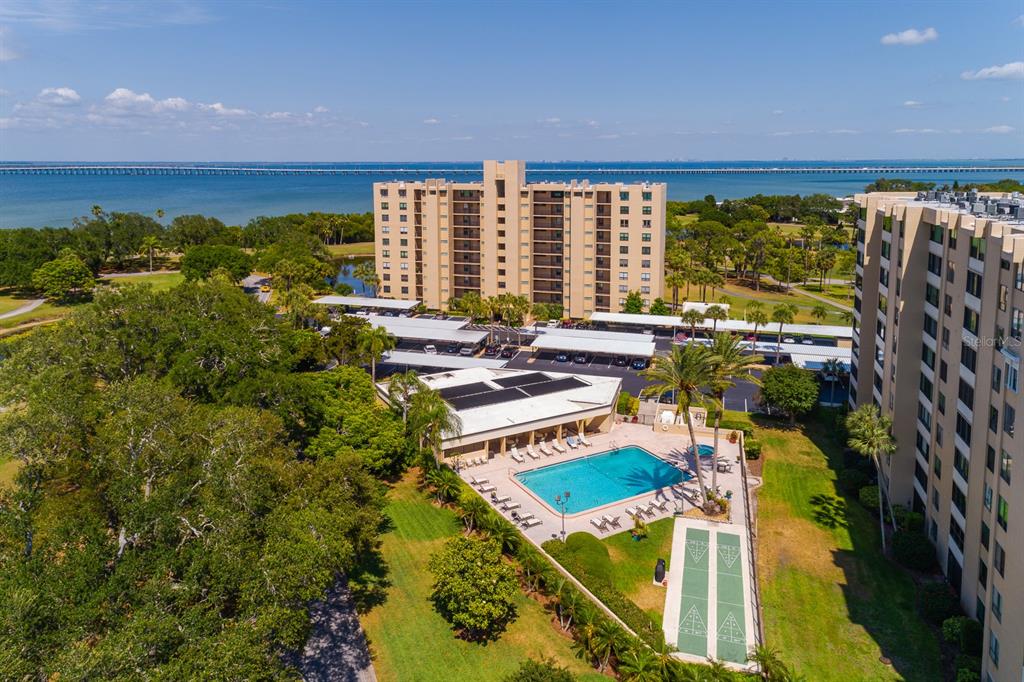 An aerial view shows a multi-story apartment building with a swimming pool and parking area — 2620 COVE CAY DRIVE UNIT 904, CLEARWATER, FL