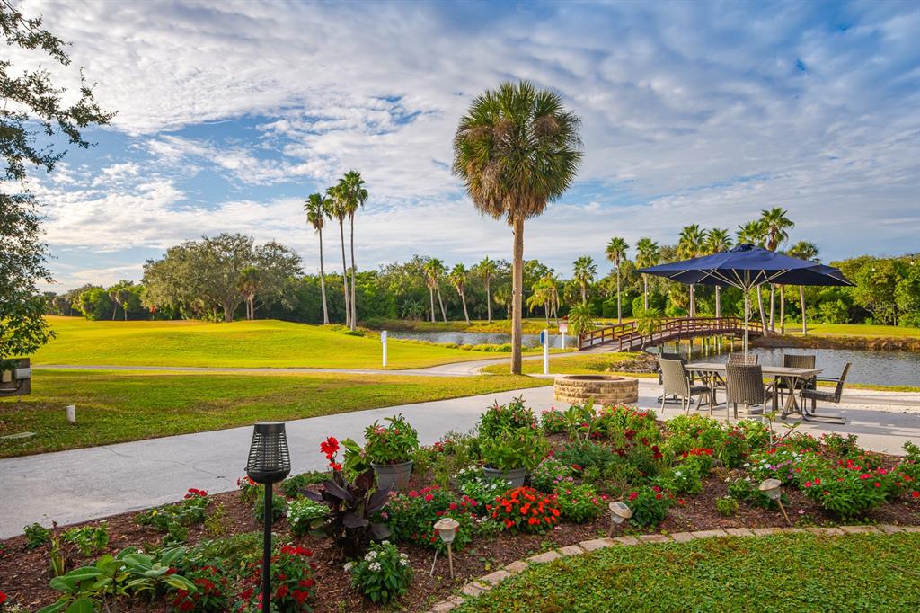 A patio with a dining set and fire pit overlooks a golf course and pond — 2620 COVE CAY DRIVE UNIT 904, CLEARWATER, FL