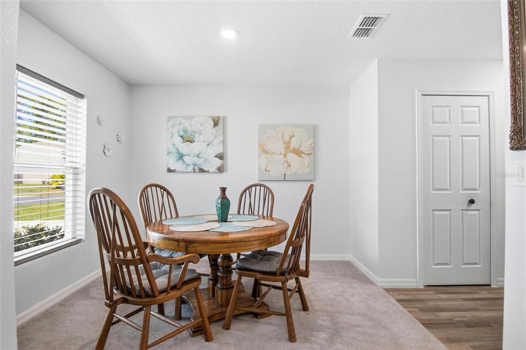 A dining area features a round wooden table, four chairs, and two floral wall canvases — 8 POST OAK LANE, PALM COAST, FL