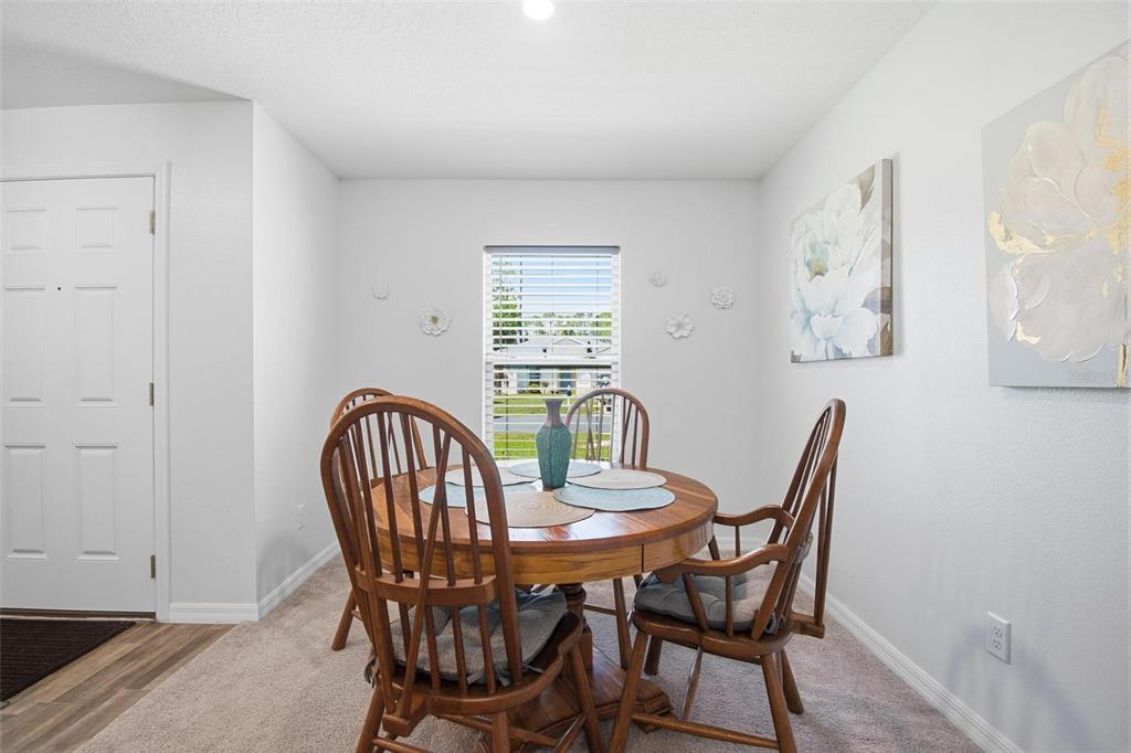 A dining area features a round wooden table with four chairs on carpeted flooring — 8 POST OAK LANE, PALM COAST, FL