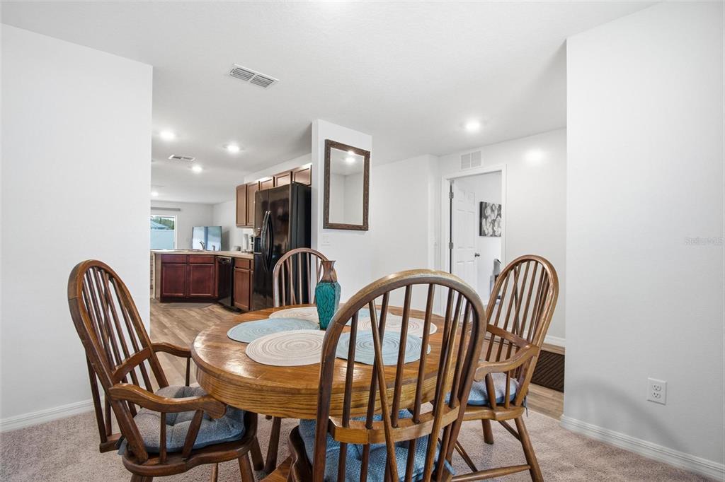 A dining area with a round wooden table and chairs overlooks an open kitchen — 8 POST OAK LANE, PALM COAST, FL