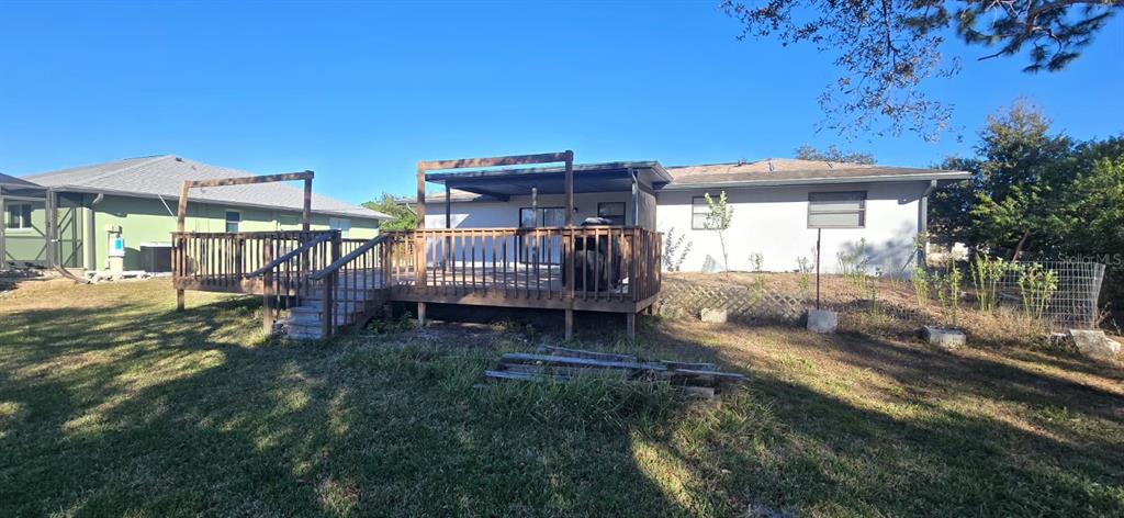 The backyard features a wooden deck with a pergola structure attached to a house — 525 ALTOONA STREET NW, PORT CHARLOTTE, FL