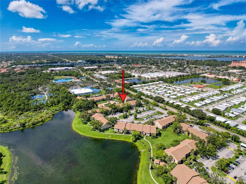 An aerial view shows a multi-unit residential complex situated next to a large pond — 4057 N CROCKERS LAKE BOULEVARD UNIT 23, SARASOTA, FL