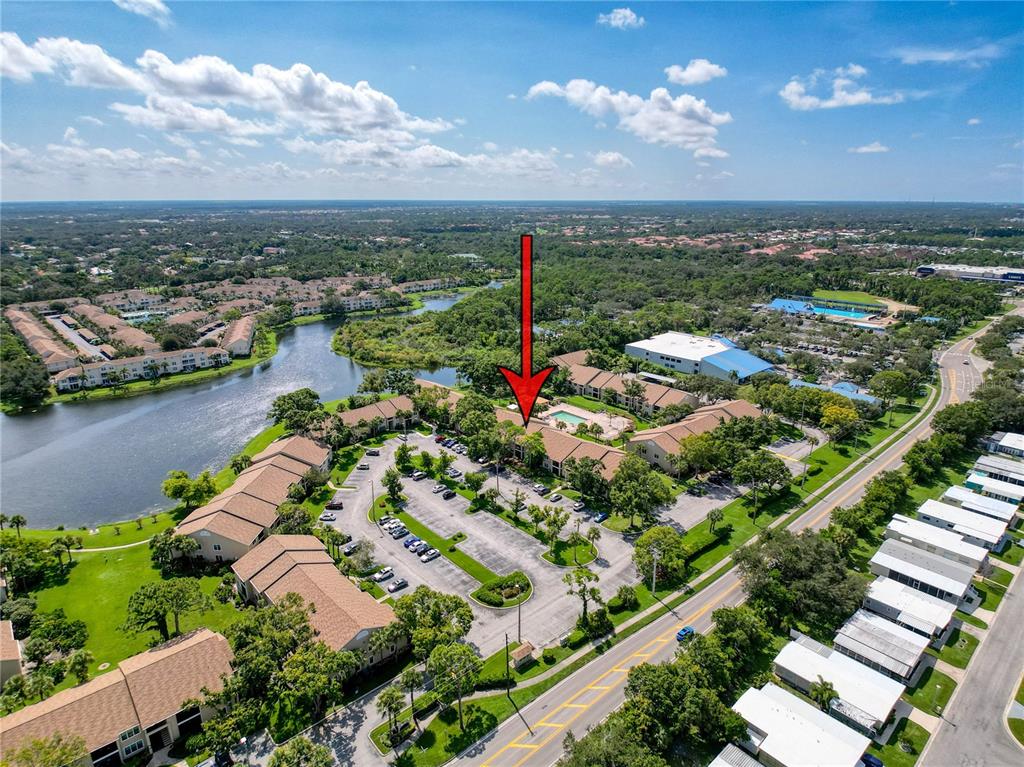 An aerial view shows a multi-story apartment complex with a swimming pool and parking lot — 4057 N CROCKERS LAKE BOULEVARD UNIT 23, SARASOTA, FL