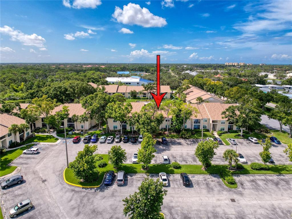 An aerial view shows a multi-story apartment complex with a parking lot and trees — 4057 N CROCKERS LAKE BOULEVARD UNIT 23, SARASOTA, FL