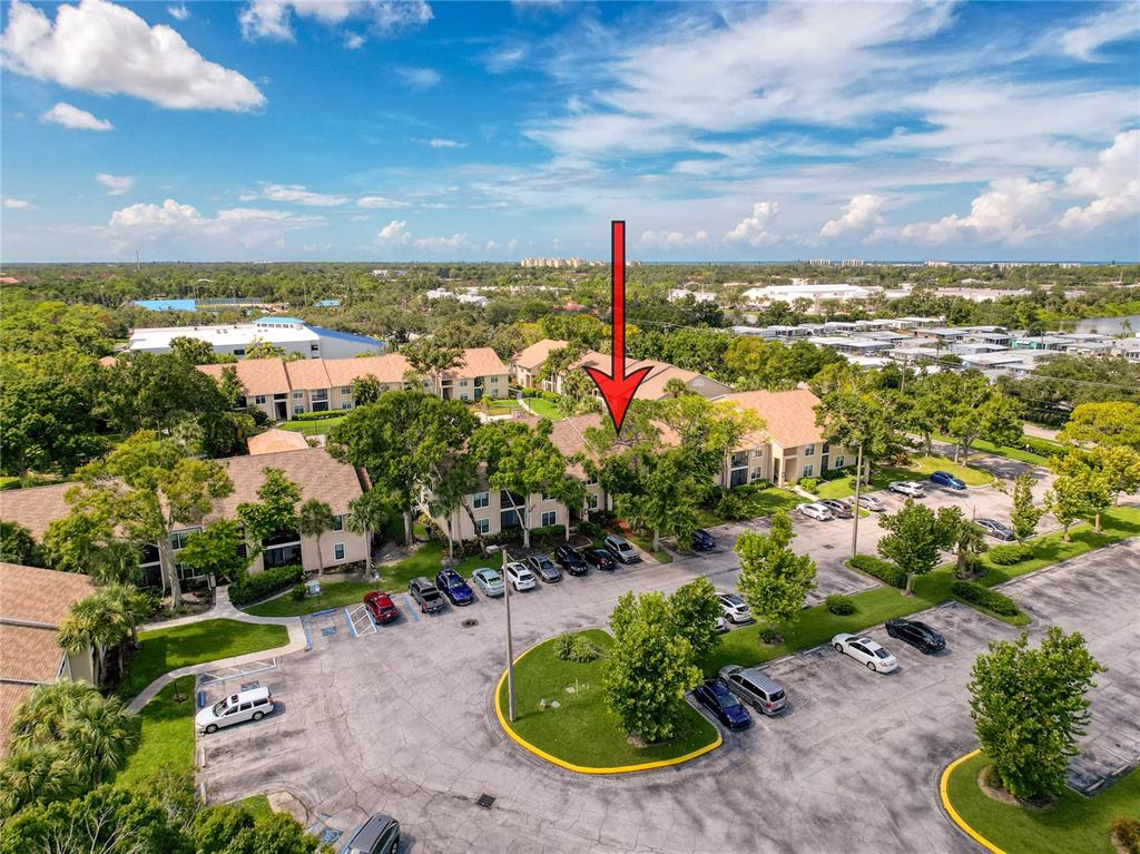 An aerial view shows a multi-story apartment complex with a parking lot and surrounding trees — 4057 N CROCKERS LAKE BOULEVARD UNIT 23, SARASOTA, FL