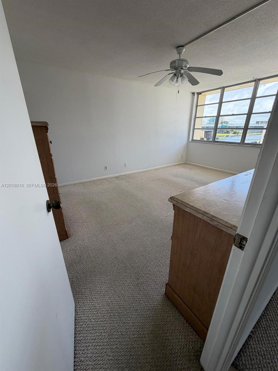 A carpeted bedroom features a ceiling fan and a large window overlooking a waterway — 1817 S Ocean Dr # 319, Hallandale Beach FL 33009, HALLANDALE BEACH, FL