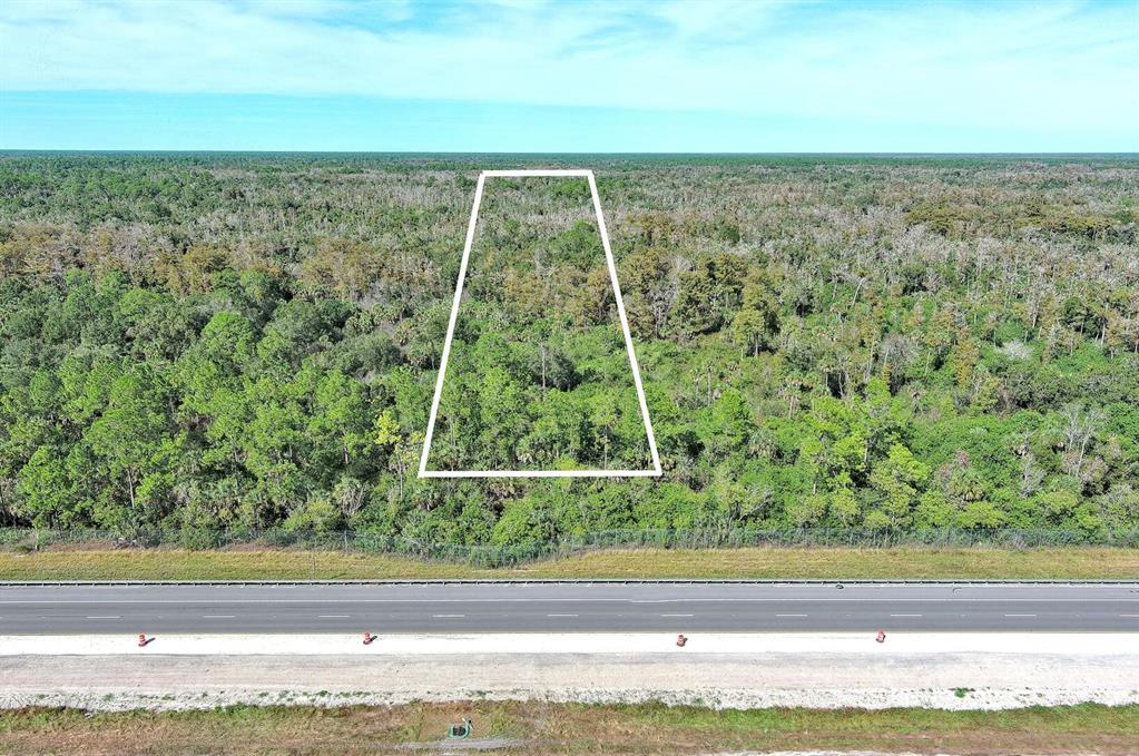 An aerial view shows a trapezoidal plot of land outlined in white bordering a highway — 4345 42ND AVENUE SE, NAPLES, FL