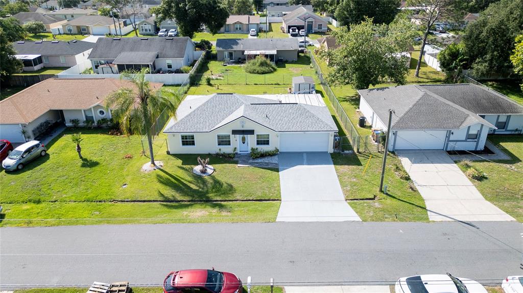 An aerial view shows a single-story house with a gray roof and concrete driveway — 256 CRANBROOK DRIVE, KISSIMMEE, FL