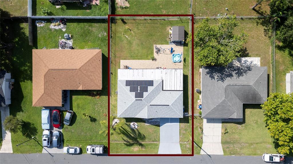 An aerial view shows a house with solar panels, a backyard patio, and a storage shed — 256 CRANBROOK DRIVE, KISSIMMEE, FL