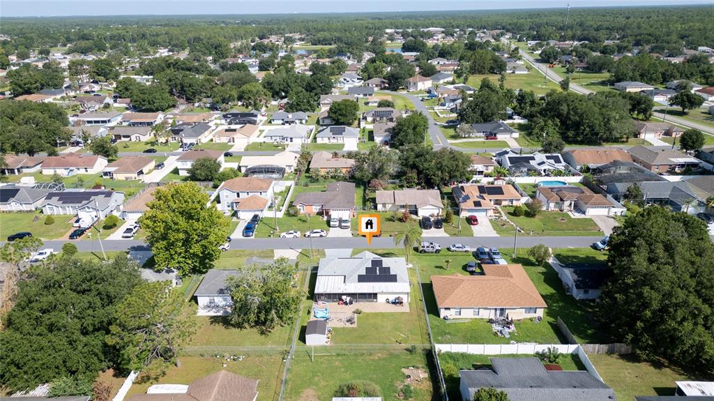An aerial view shows a residential neighborhood with a house featuring solar panels — 256 CRANBROOK DRIVE, KISSIMMEE, FL