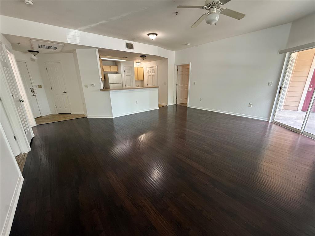 An open-concept living room features dark wood flooring, a kitchen breakfast bar, and sliding doors — 2015 ERVING CIRCLE UNIT 102, OCOEE, FL