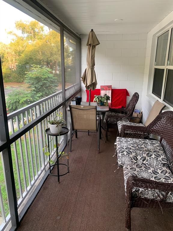A screened-in porch features wicker furniture, a small dining set, and a view of trees — 700 E AIRPORT BOULEVARD UNIT B6, SANFORD, FL
