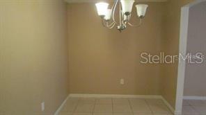 A dining area features beige walls, light-colored floor tiles, and a hanging chandelier — 700 E AIRPORT BOULEVARD UNIT B6, SANFORD, FL