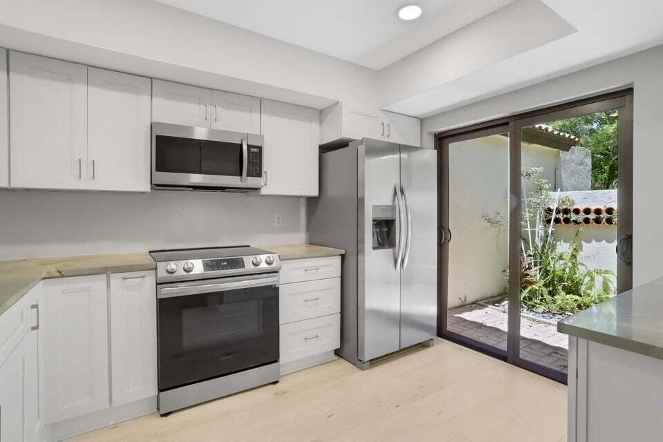 A kitchen with white cabinets, stainless steel appliances, and a sliding glass door to a patio — 3113 Kingswood Terrace, Boca Raton FL 33431, BOCA RATON, FL