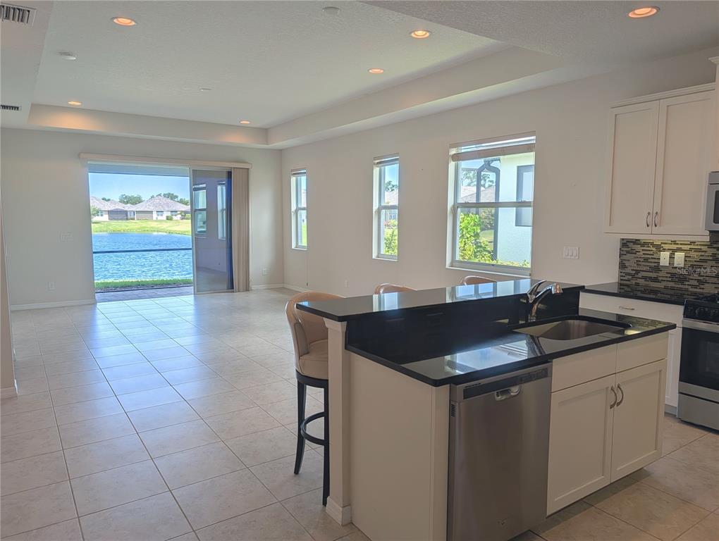 A kitchen island with a black countertop overlooks an open living area with lake views — 7528 ALUMNI TRAIL, SARASOTA, FL