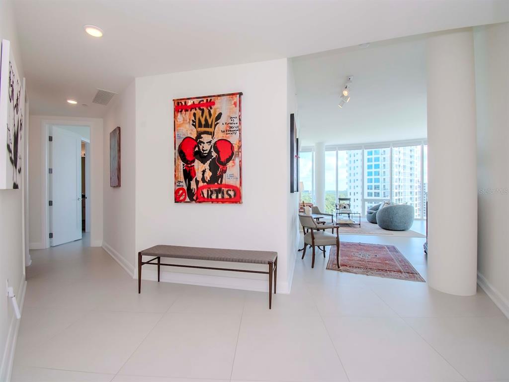 A modern entryway features a bench, a large boxing-themed artwork, and a view into a living room — 2900 W BAY TO BAY BOULEVARD UNIT 1203, TAMPA, FL