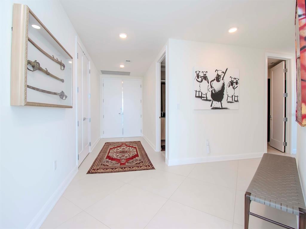 A bright hallway features white walls, tile flooring, a patterned rug, and framed wall art — 2900 W BAY TO BAY BOULEVARD UNIT 1203, TAMPA, FL