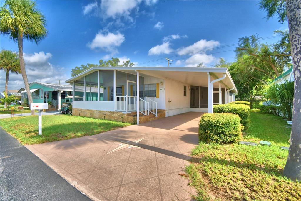 A single-story manufactured home features a screened-in porch, a carport, and a paved driveway — 4027 ROLLING OAKS DRIVE, WINTER HAVEN, FL