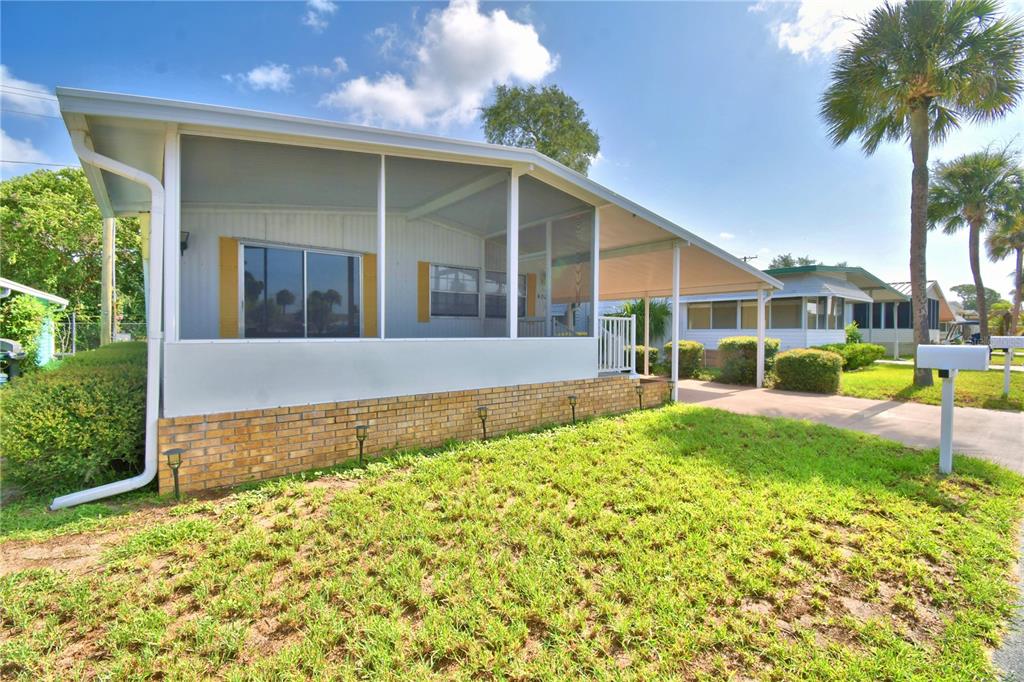A mobile home with a screened-in porch, brick skirting, and an attached carport — 4027 ROLLING OAKS DRIVE, WINTER HAVEN, FL