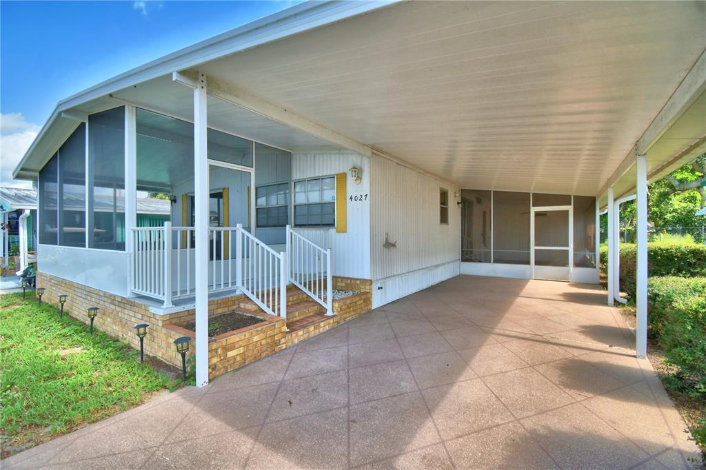 A mobile home exterior features a screened-in porch, a brick foundation, and a covered carport — 4027 ROLLING OAKS DRIVE, WINTER HAVEN, FL