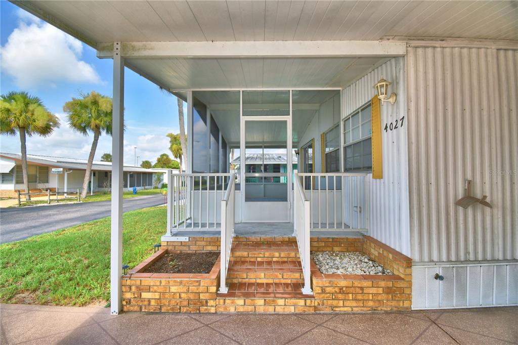 A covered porch with brick steps leads to a screened-in entrance of a mobile home — 4027 ROLLING OAKS DRIVE, WINTER HAVEN, FL