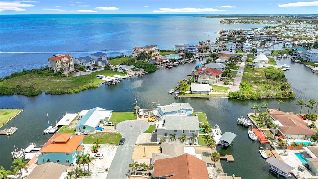 An aerial view shows waterfront homes with private docks along a canal leading to the ocean — 13816 VICTOR AVENUE, HUDSON, FL