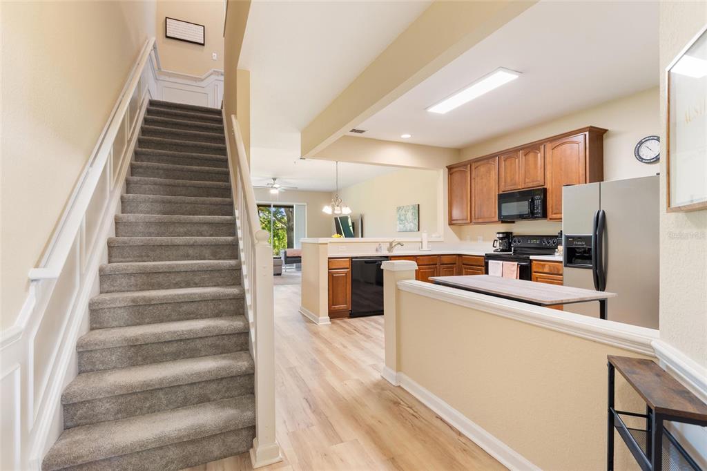 A kitchen features wood cabinets, stainless steel appliances, and a light-colored island countertop — 6342 DAYSBROOK DRIVE UNIT 103, ORLANDO, FL