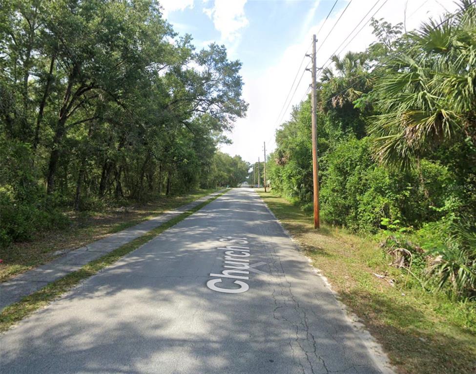 A paved road named Church St runs through a wooded area with utility poles — CHURCH, LAKE HELEN, FL