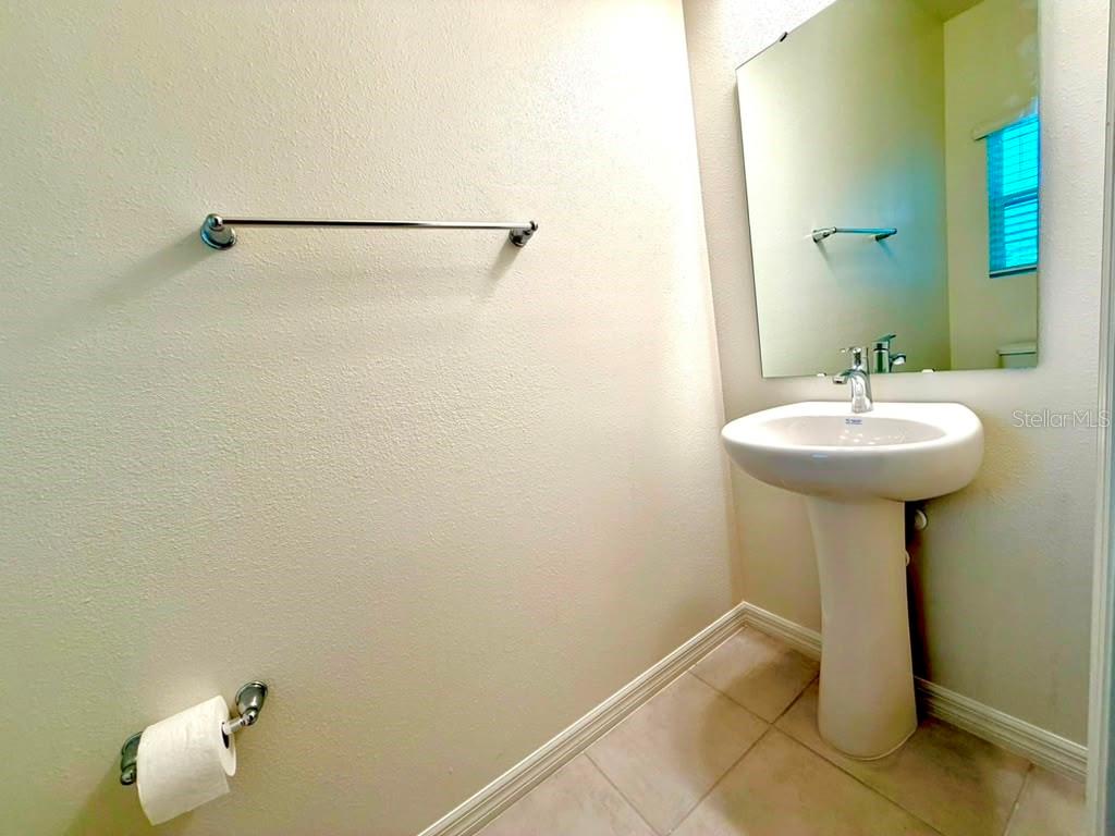 A half bathroom features a pedestal sink, a wall-mounted mirror, and a towel bar — 16615 LUMINARY LOOP, CLERMONT, FL