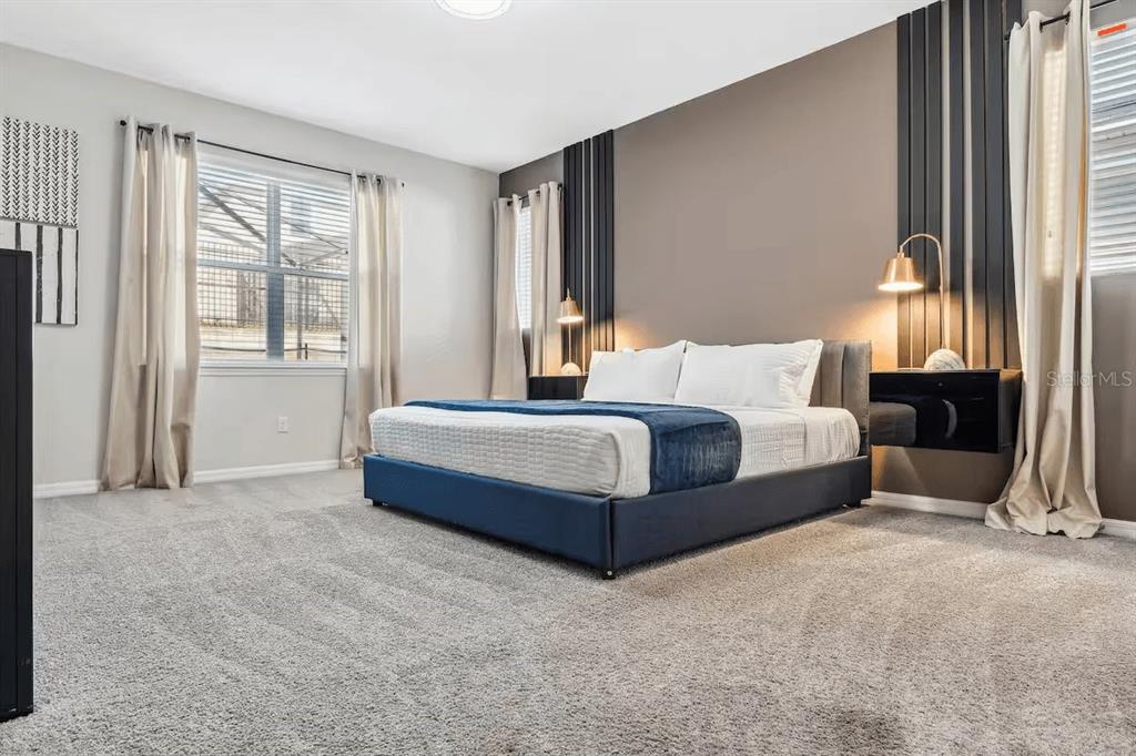 A bedroom features a blue bed, gray carpet, and dark vertical wall accents — 1820 SANDY PARK TRAIL, KISSIMMEE, FL