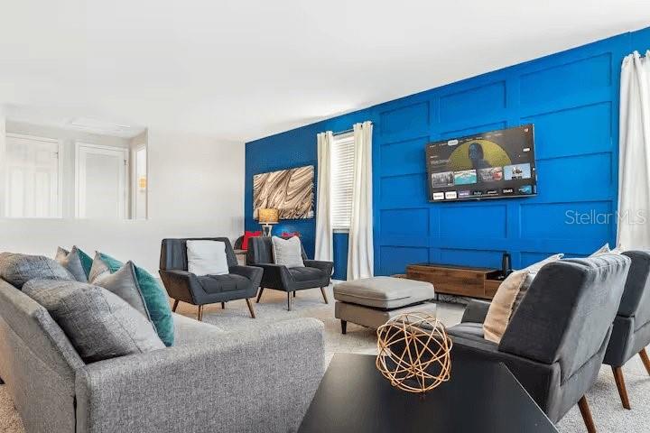 A living room features a blue paneled accent wall with a mounted television — 1820 SANDY PARK TRAIL, KISSIMMEE, FL