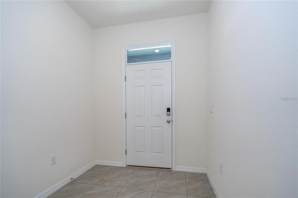 An entryway with a white door, transom window, and light-colored tile flooring — 34293 SORREL MINT DRIVE, WESLEY CHAPEL, FL