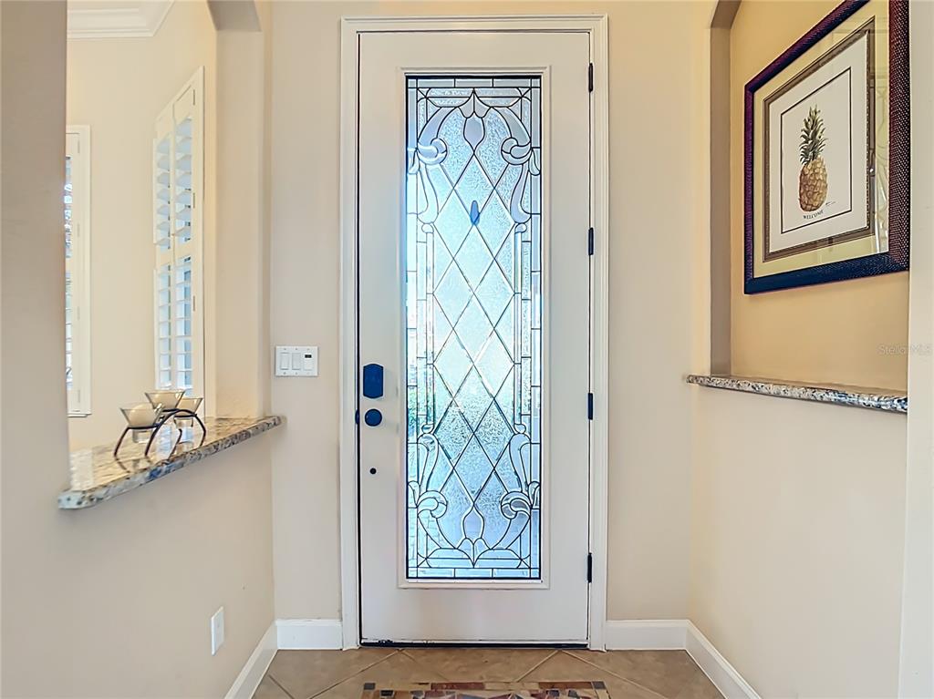 An entryway features a white front door with decorative glass, tile flooring, and granite counters — 114 RIMINI WAY, NORTH VENICE, FL