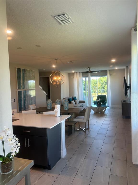 An open-concept living and dining area features a kitchen island, tile floors, and large windows — 824 DRIVING RANGE COURT, REUNION, FL