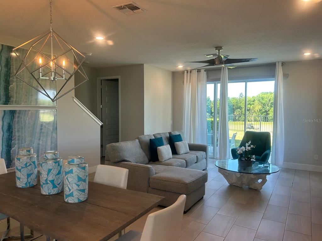A dining area and living room feature a geometric chandelier, sectional sofa, and glass-topped table — 824 DRIVING RANGE COURT, REUNION, FL