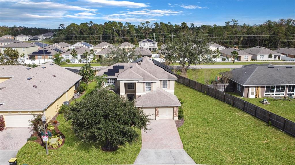 An aerial view of a two-story suburban house with solar panels and a paved driveway — 112 CYPRESS POINTE COURT, DAVENPORT, FL