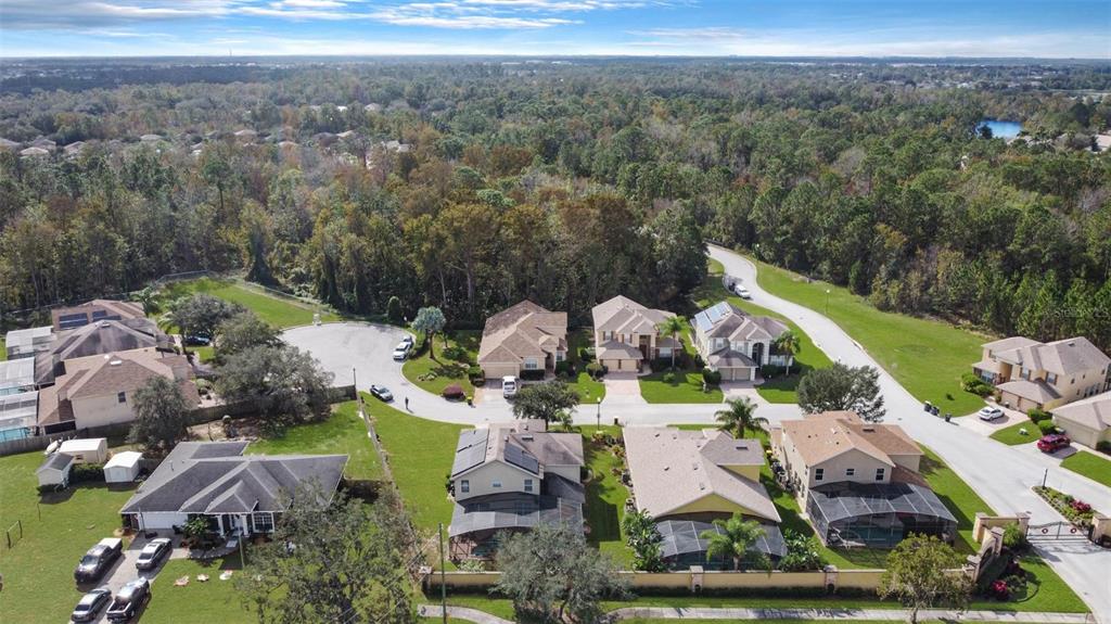 An aerial view shows a suburban neighborhood with several single-family homes and surrounding wooded areas — 112 CYPRESS POINTE COURT, DAVENPORT, FL