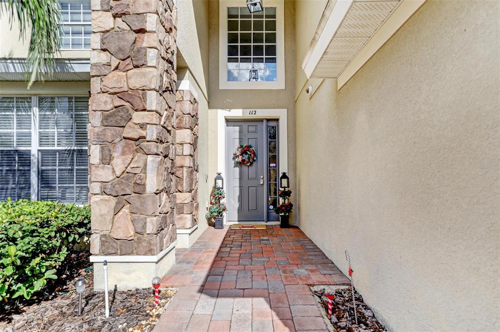 A stone-accented entryway features a gray front door, a brick walkway, and a large window — 112 CYPRESS POINTE COURT, DAVENPORT, FL