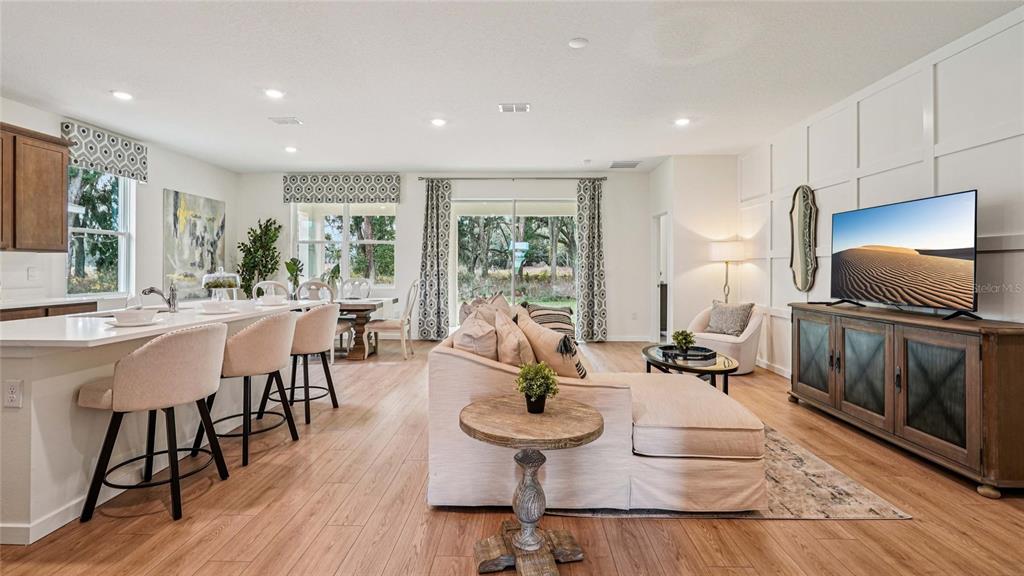 An open-concept living room and kitchen feature light wood flooring and a paneled accent wall — 4574 SW 71ST LANE ROAD, OCALA, FL