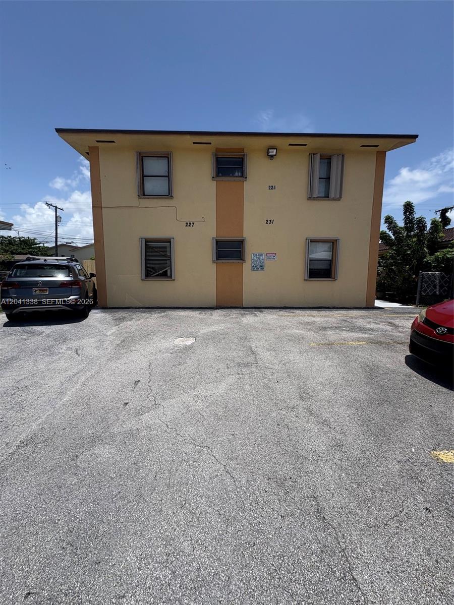 A two-story, yellow apartment building with a paved parking lot in the foreground — 231 E 7th St # 202, Hialeah FL 33010, HIALEAH, FL