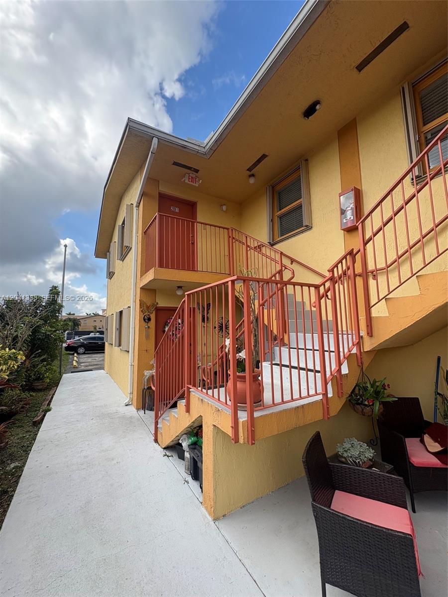 An exterior view shows a yellow building with orange metal stairs and railings — 231 E 7th St # 202, Hialeah FL 33010, HIALEAH, FL