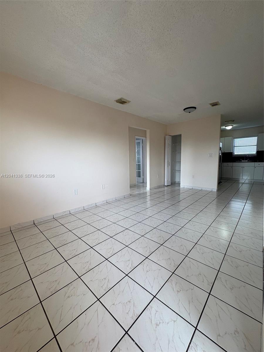 An exterior view of a second-floor apartment entrance with a red door and metal railing — 231 E 7th St # 202, Hialeah FL 33010, HIALEAH, FL